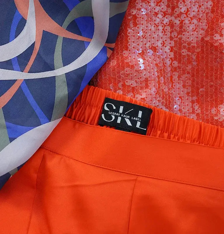 A pair of orange pants and a shirt with the label skl.